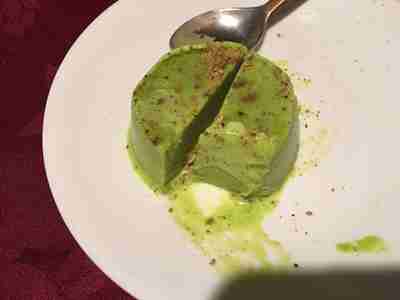 Pistachio Kulfi Indian ice cream dessert, sliced in half and served on a white plate with a spoon